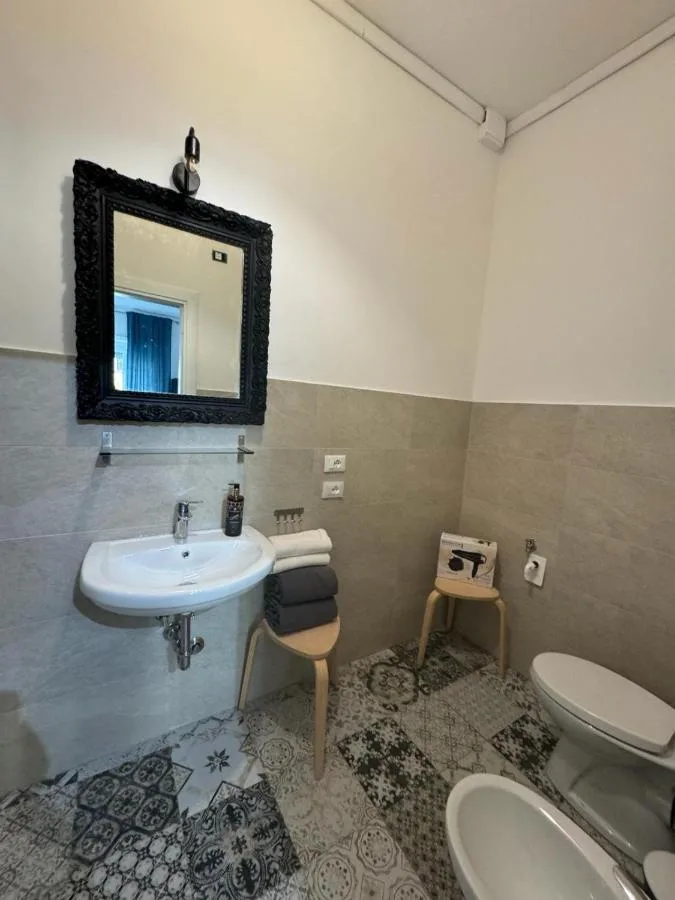 Il bagno con lo specchio dalla cornice nera e le maioliche a disegni