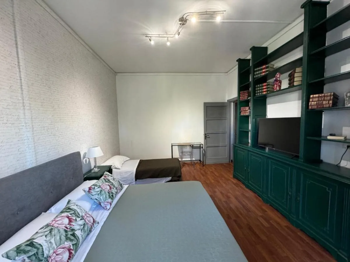 La camera con la libreria verde a tutta parete e la TV